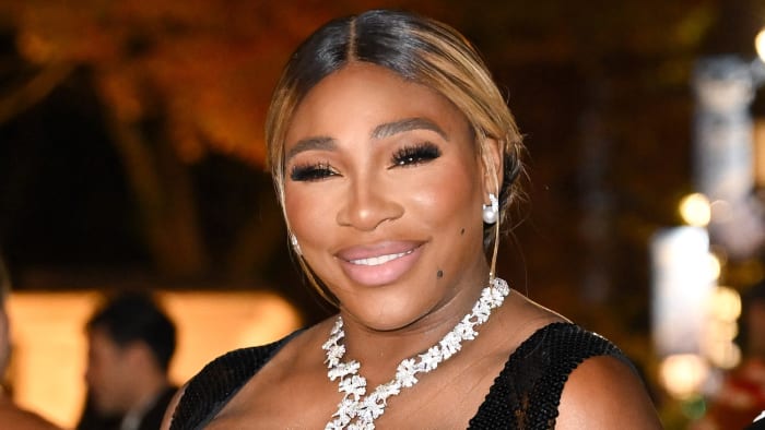 Serena Williams poses in a black sparkly dress and a floral diamond necklace.